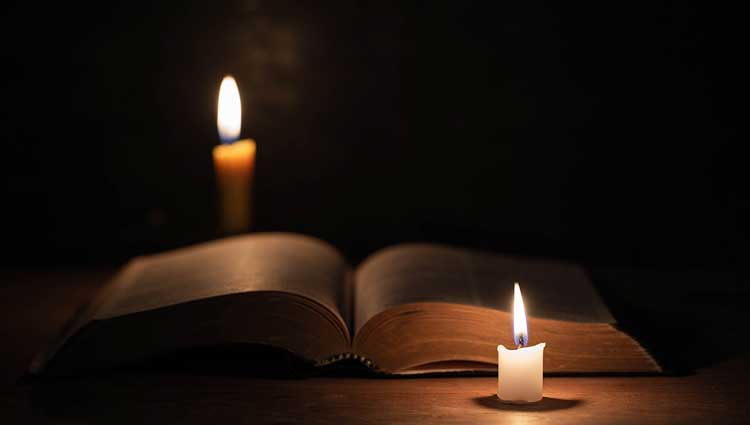 Two candles with an open book in memoriam conveying wisdom