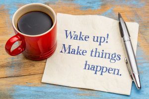 An image of black coffee in a red mug, sitting on a napkin that has "Wake up! Make things happen." written on it, to illustrate a blog post about nonprofits facing a $65 Billion giving decline.