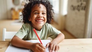 A smiling child writes a thank-you letter. Thanking donors is important; adding an impact statement makes them feel like partners in your mission.
